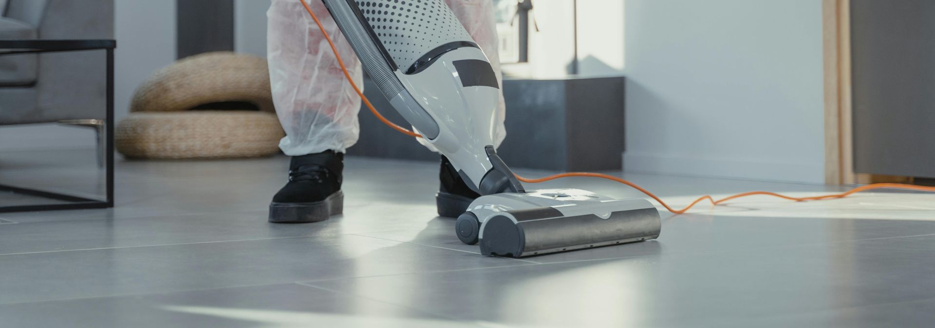 Person Using a Vacuum on Floor Tiles